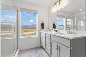 Full bathroom featuring double vanity, a sink, a mountain view, and a healthy amount of sunlight