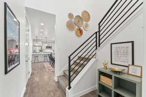 Staircase with baseboards, wood finished floors, and recessed lighting