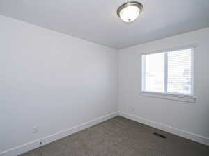 Empty room with visible vents, baseboards, and dark colored carpet