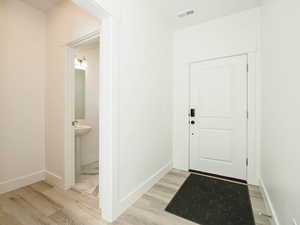 Doorway featuring light wood-type flooring, baseboards, and visible vents