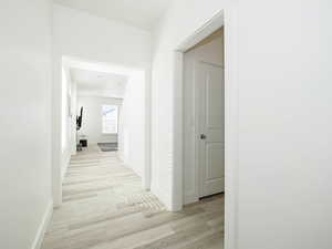 Hallway with light wood-style floors and baseboards