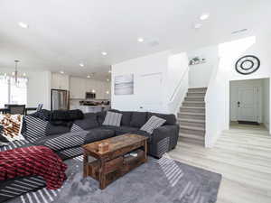 Living area with recessed lighting, visible vents, light wood-style flooring, a chandelier, and stairs