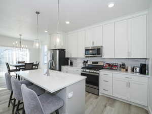 Kitchen with a breakfast bar area, appliances with stainless steel finishes, decorative backsplash, and a sink