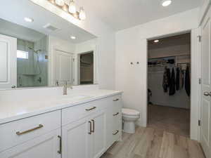 Full bathroom with toilet, wood finished floors, vanity, visible vents, and a shower stall