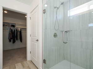 Full bath featuring a shower stall, a spacious closet, and wood finished floors