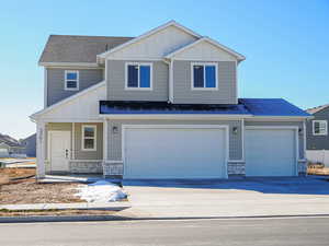 Craftsman-style house with stone siding, board and batten siding, and concrete driveway