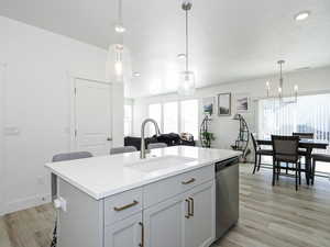 Kitchen with stainless steel dishwasher, a textured ceiling, light wood-style floors, and a sink