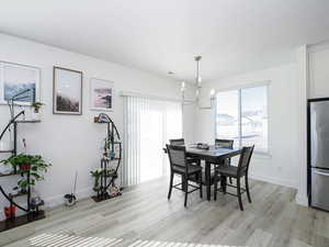 Dining room with a chandelier, light wood-style flooring, and baseboards