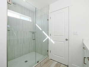 Full bathroom featuring a shower stall, vanity, and wood finished floors