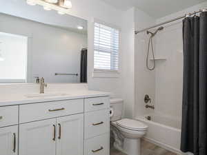 Full bathroom with toilet, wood finished floors, shower / bath combination with curtain, and vanity