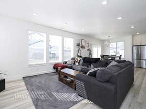 Living area featuring a chandelier, light wood-type flooring, baseboards, and recessed lighting