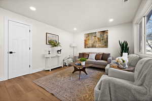 Living room with recessed lighting, visible vents, and wood finished floors