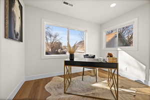 Home office with recessed lighting, wood finished floors, visible vents, and baseboards