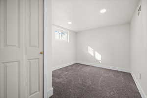 Unfurnished room featuring recessed lighting, dark carpet, a textured ceiling, and baseboards