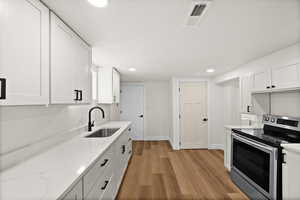 Kitchen with a sink, visible vents, white cabinetry, light wood finished floors, and stainless steel range with electric stovetop