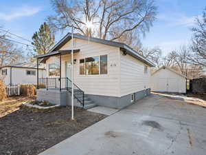 Bungalow with an outbuilding, driveway, and a storage unit