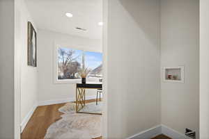 Clothes washing area featuring hookup for a washing machine, visible vents, wood finished floors, laundry area, and baseboards