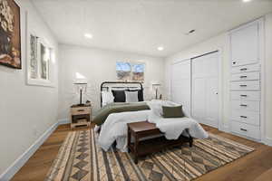 Bedroom with recessed lighting, visible vents, a textured ceiling, wood finished floors, and baseboards