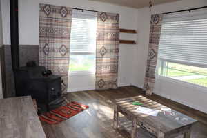 Sitting room featuring a wood stove, wood finished floors, and baseboards