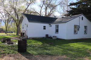View of side of home with a lawn, central AC, and roof with shingles