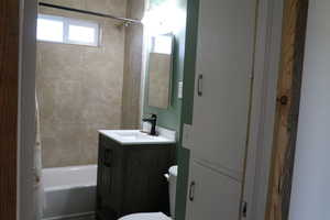 Bathroom with toilet, vanity, and shower / bathtub combination with curtain