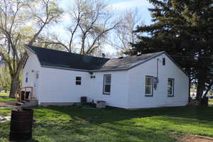 View of property exterior with a lawn and roof with shingles