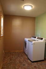 Laundry room featuring washer and dryer and brick floors