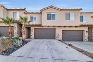 Mediterranean / spanish house featuring an attached garage, driveway, stone siding, and stucco siding