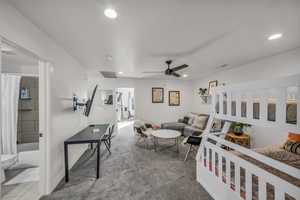 Carpeted living room featuring ceiling fan, visible vents, and recessed lighting