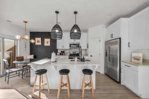 Kitchen featuring appliances with stainless steel finishes, a breakfast bar area, a sink, and decorative backsplash