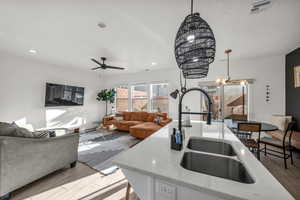 Kitchen with hanging light fixtures, wood finished floors, a sink, and visible vents