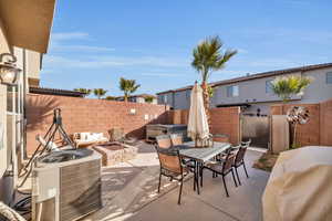 View of patio featuring an outdoor fire pit, a fenced backyard, outdoor dining space, and central air condition unit