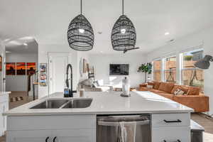 Kitchen with dishwasher, open floor plan, light wood-style floors, white cabinetry, and a sink