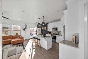 Kitchen featuring decorative backsplash, appliances with stainless steel finishes, open floor plan, wood finished floors, and a sink