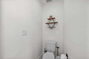 Bathroom with baseboards, visible vents, and toilet