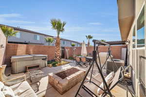 View of patio with a hot tub, an outdoor fire pit, outdoor dining space, cooling unit, and a fenced backyard