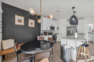 Kitchen featuring white cabinetry, wood tiled floor, appliances with stainless steel finishes, and light countertops