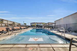 Community pool with a patio area, fence, and a residential view