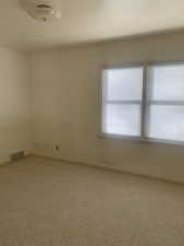 Carpeted empty room with visible vents and baseboards