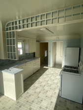 Kitchen with white cabinets, a sink, tasteful backsplash, white appliances, and brick floor