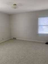 Spare room featuring baseboards, visible vents, and carpet flooring