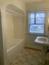 Bathroom with a wealth of natural light, baseboards, and shower / bathtub combination