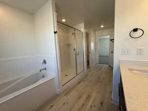 Full bath featuring wood finished floors, a shower stall, vanity, and a bath