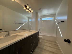 Bathroom with double vanity, wood finished floors, a sink, and visible vents