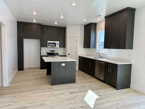 Kitchen with visible vents, light wood-style flooring, appliances with stainless steel finishes, a sink, and a kitchen island