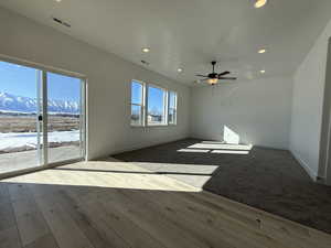 Unfurnished room with visible vents, a mountain view, baseboards, and wood finished floors