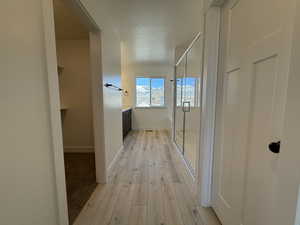 Hall featuring light wood finished floors, baseboards, and a textured ceiling