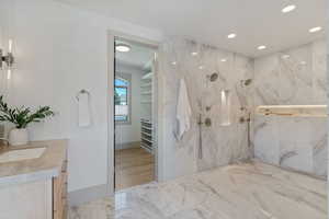 Bathroom featuring recessed lighting, vanity, marble finish floor, a marble finish shower, and a walk in closet