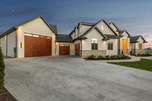 View of front of house featuring a garage, driveway, stone siding, and stucco siding