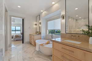 Full bath featuring a freestanding tub, recessed lighting, marble finish floor, and a sink